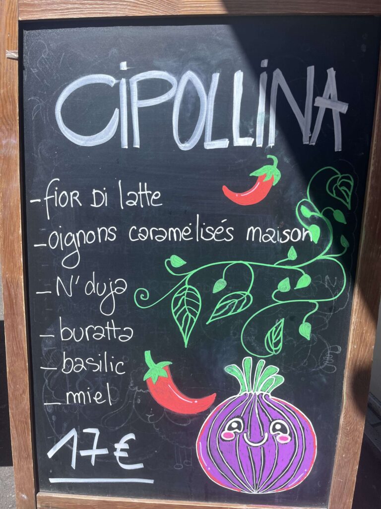 Ardoise de Semola Pizzeria à Paris présentant la pizza Cipollina avec fior di latte, oignons caramélisés maison, N'duja, burrata, basilic et miel.