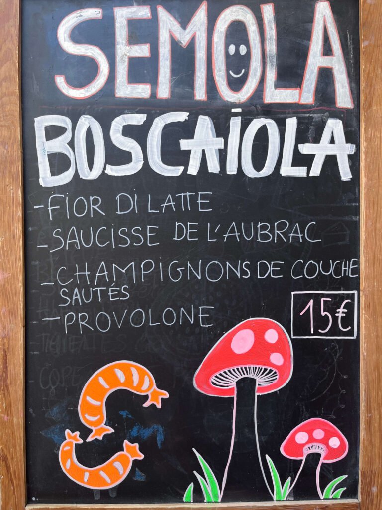 Ardoise de Semola Pizzeria à Paris présentant la pizza Semola Boscaiola avec fior di latte, saucisse de l'Aubrac, champignons de couche sautés et provolone.